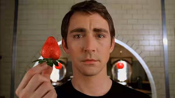 Ned (Lee Pace) holds a large strawberry toward the camera