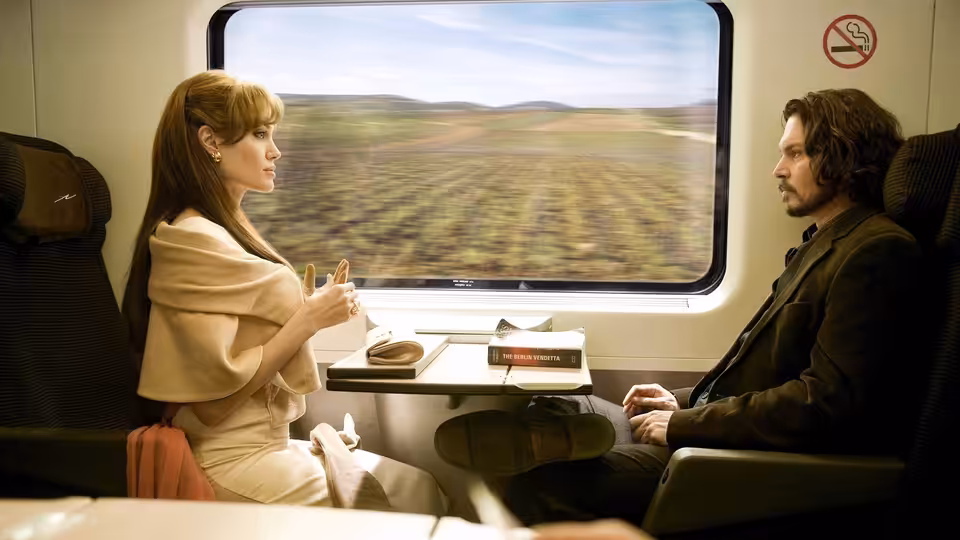 Elise Clifton-Ward (Angelina Jolie) and Frank Tupelo (Johnny Depp) sit opposite each other on a train