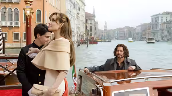 Elise Clifton-Ward (Angelina Jolie) stands beside a uniformed man as Frank Tupelo (Johnny Depp) approaches by boat