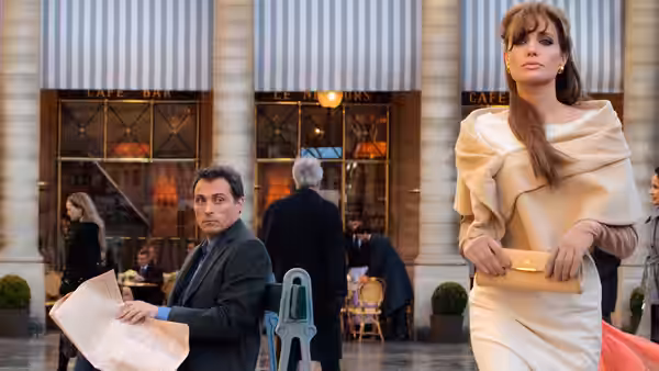 Elise Clifton-Ward (Angelina Jolie) walks past a café while Inspector John Acheson (Paul Bettany) reads a newspaper