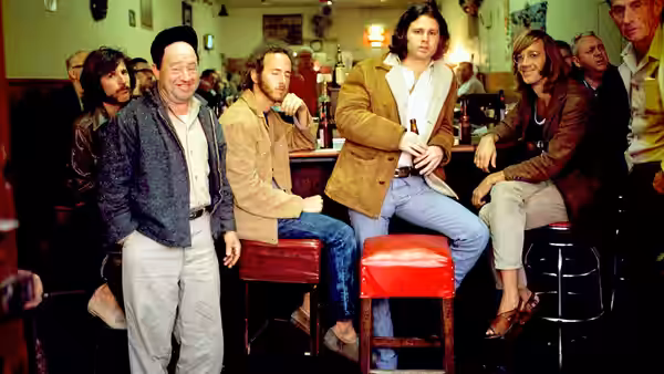 Jim Morrison and fellow Doors members gather around stools in a diner