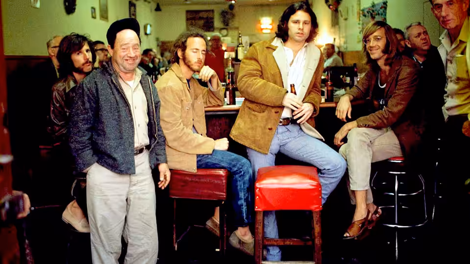 Jim Morrison and fellow Doors members gather around stools in a diner