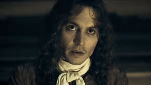 Rochester (Johnny Depp) stares ahead in a dimly lit room
