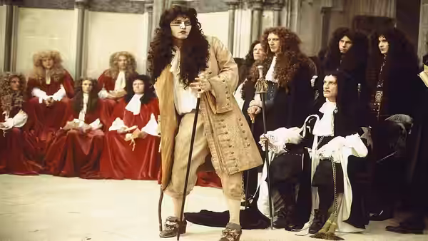Rochester (Johnny Depp) stands before the seated king and courtiers in a royal chamber