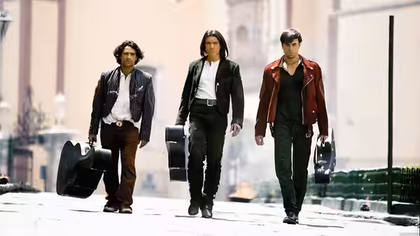 El Mariachi (Antonio Banderas) and two musicians walk down a city street carrying guitar cases