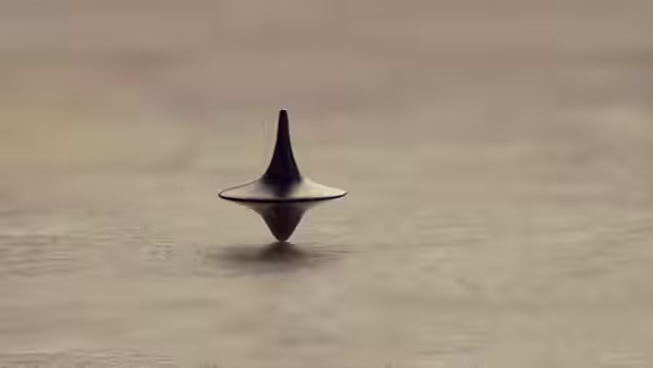A black spinning top balanced upright on a wooden table