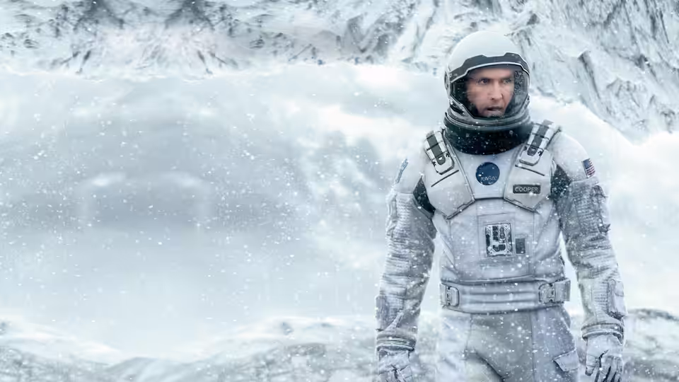 Cooper (Matthew McConaughey) in a spacesuit amid falling snow on an icy planet