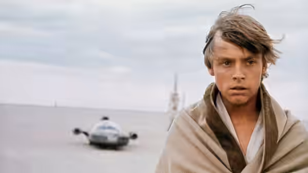 Luke Skywalker (Mark Hamill) stands on a desert plain with a landspeeder behind him