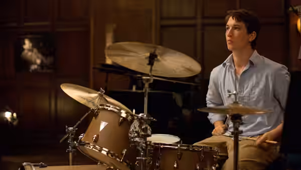 Andrew (Miles Teller) sits at the drum kit looking upward