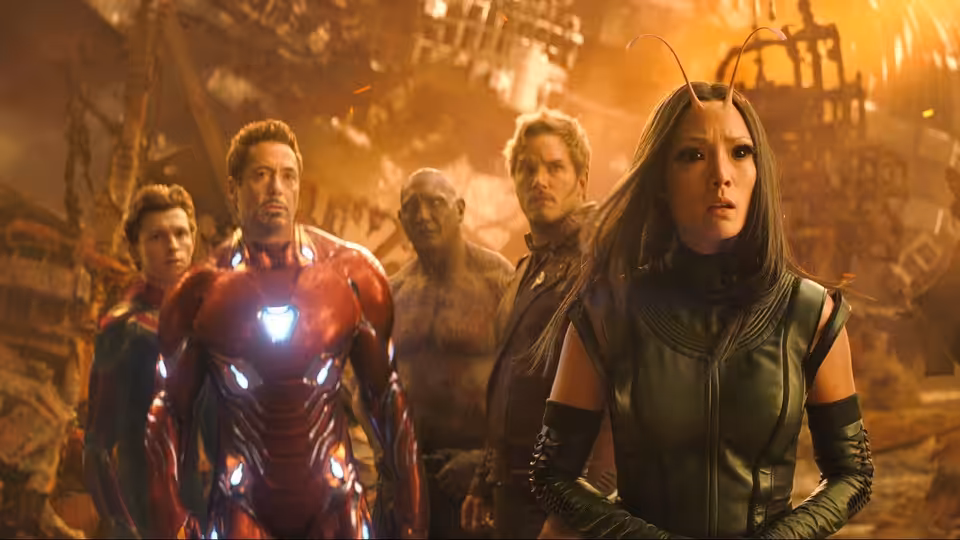 Iron Man and Black Widow leading a group of heroes in a ruined city