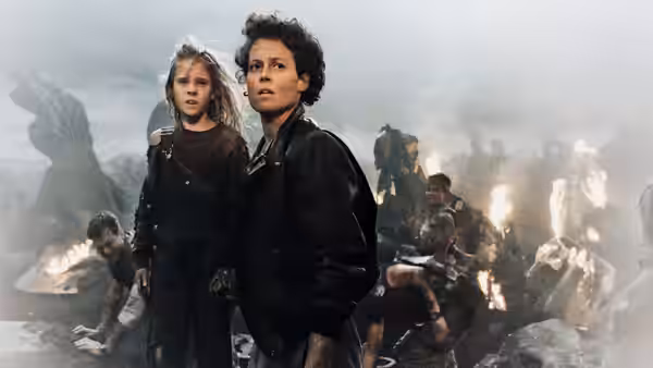 Ripley (Sigourney Weaver) and Newt (Carrie Henn) stand amid burning debris and survivors