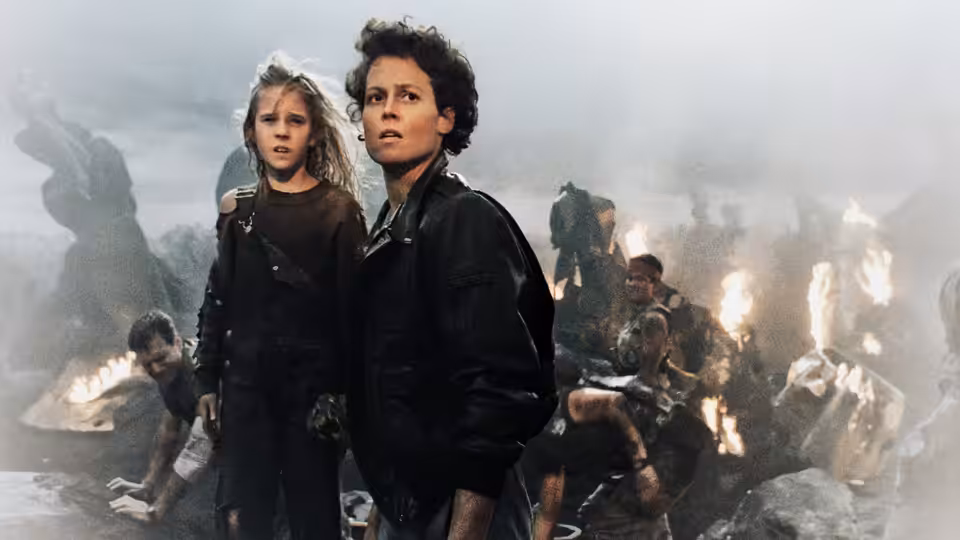 Ripley (Sigourney Weaver) and Newt (Carrie Henn) stand amid burning debris and survivors