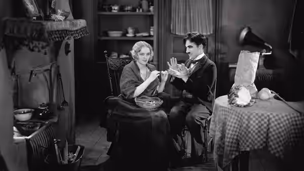 The Tramp (Charlie Chaplin) holds hands with the Blind Girl (Virginia Cherrill) indoors