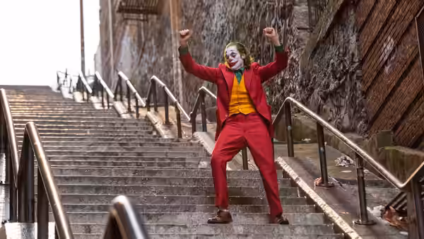 Arthur Fleck (Joaquin Phoenix) standing with arms raised on concrete stairs