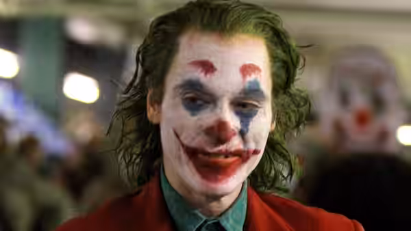 Arthur Fleck (Joaquin Phoenix) in clown makeup smiling at the camera
