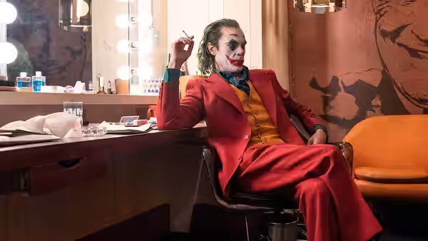 Arthur Fleck (Joaquin Phoenix) seated at a dressing room mirror in a red suit