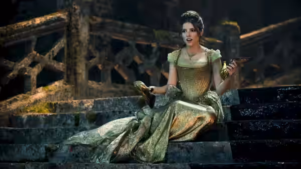 Cinderella (Anna Kendrick) sits on stone steps in her ball gown, holding a slipper