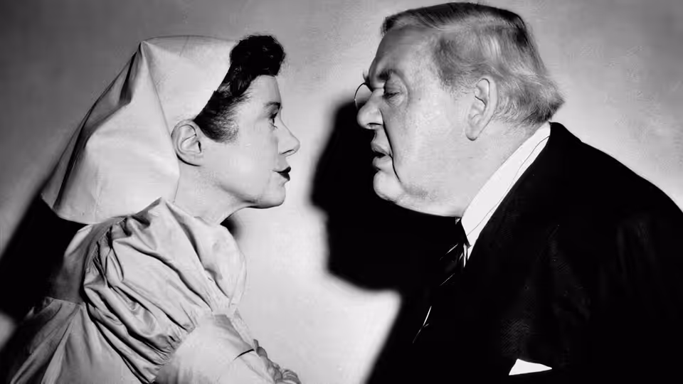 Miss Plimsoll (Elsa Lanchester) and Sir Wilfrid (Charles Laughton) stand face to face