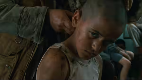 A young boy with a shaved head looks upward in a crowded space