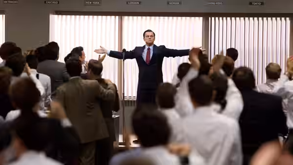 Jordan Belfort (Leonardo DiCaprio) addressing his team in a bustling brokerage office