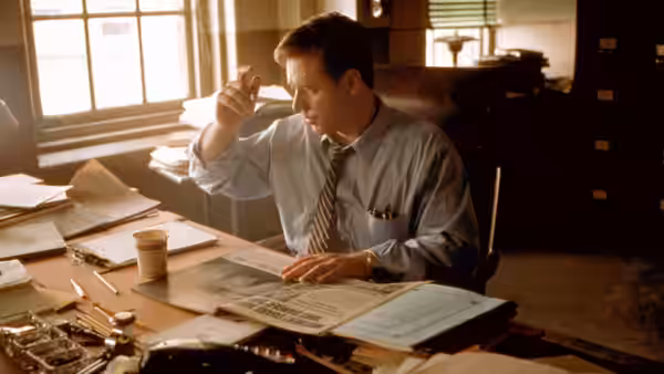John Nash (Russell Crowe) examining papers while seated at an office desk