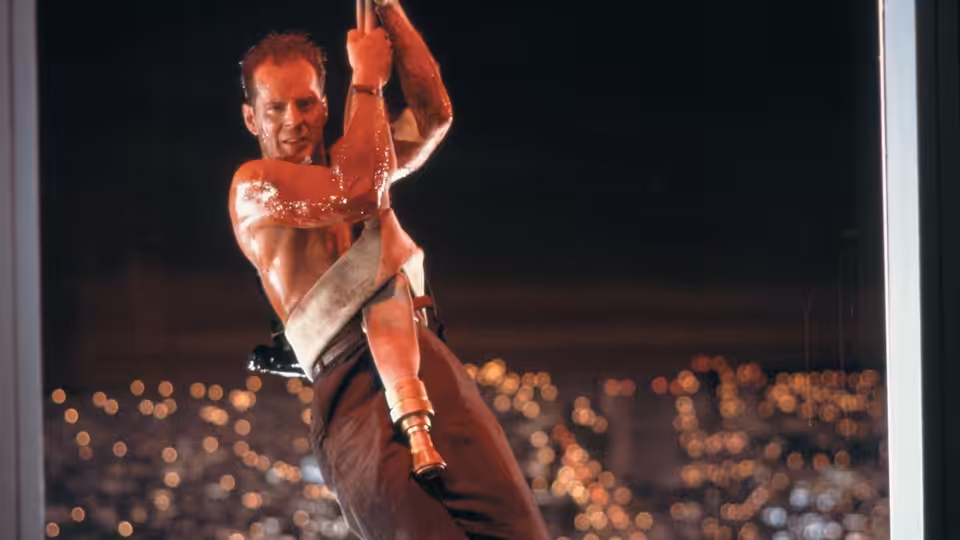 John McClane (Bruce Willis) gripping a rope outside a skyscraper at night
