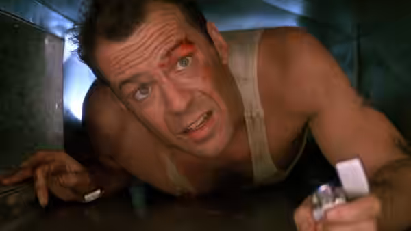 John McClane (Bruce Willis) crawling in a vent holding a lighter