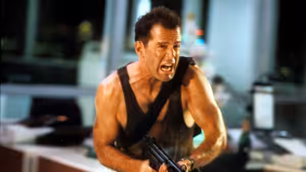John McClane (Bruce Willis) running with a gun through an office