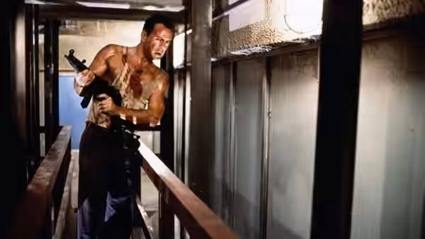 John McClane (Bruce Willis) aiming two guns on a walkway