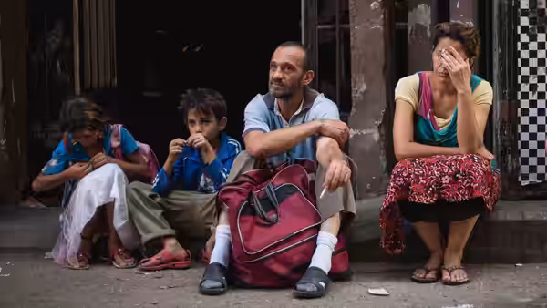 A man and woman sit on the street with two children beside them