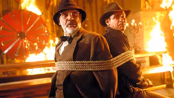 Henry Jones (Sean Connery) and Indiana Jones (Harrison Ford) bound back to back in a burning hall