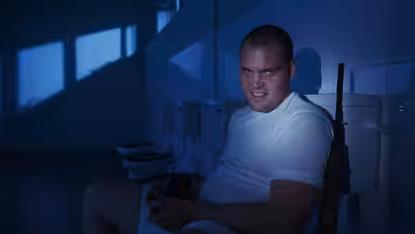 Pvt. Pyle (Vincent D'Onofrio) sits on a toilet holding a rifle in a tiled bathroom