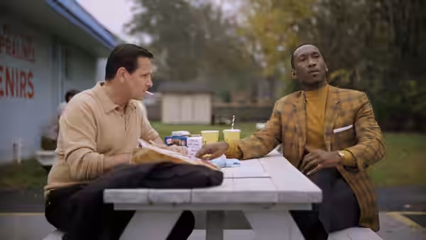Tony Lip (Viggo Mortensen) and Dr. Don Shirley (Mahershala Ali) seated at an outdoor picnic table