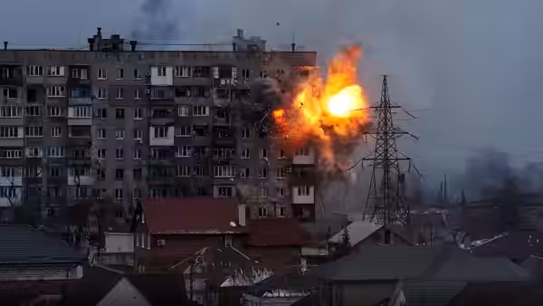 Explosion erupting from the side of a multi-story apartment building in a city