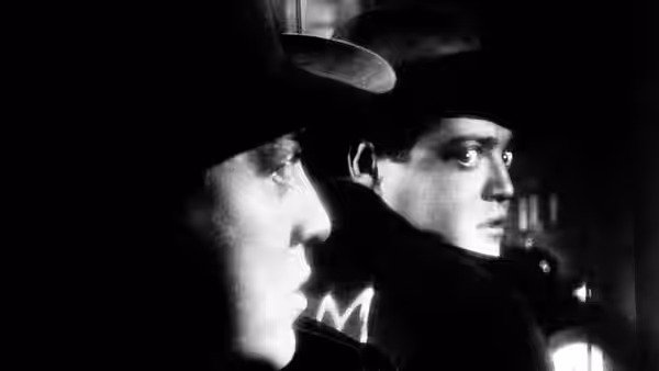 Hans Beckert (Peter Lorre) and a companion in hats watching intently