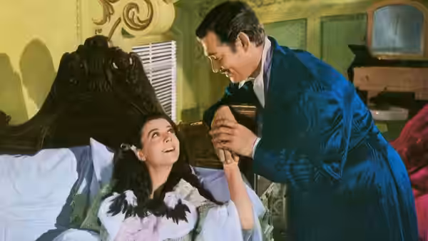 Rhett Butler (Clark Gable) holds Scarlett O'Hara's (Vivien Leigh) hand beside the bed