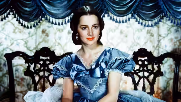 Scarlett O'Hara (Vivien Leigh) sits wearing a blue gown on an ornate chair