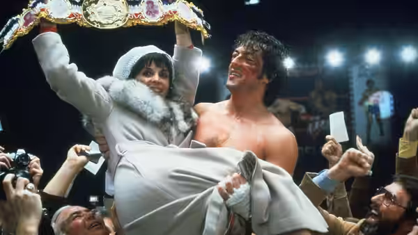 Rocky Balboa (Sylvester Stallone) lifts Adrian (Talia Shire) with a championship belt