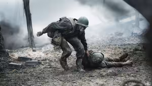 A soldier lifting an injured comrade from the muddy battlefield