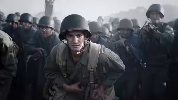 Desmond T. Doss (Andrew Garfield) crouching among soldiers on the battlefield