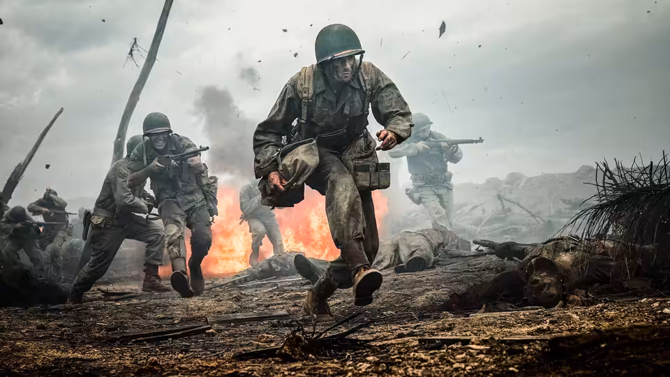 Soldiers charging forward across muddy ground amid explosions and smoke
