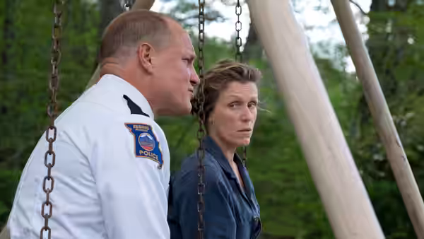A police officer and Mildred (Frances McDormand) stand chained to posts outdoors