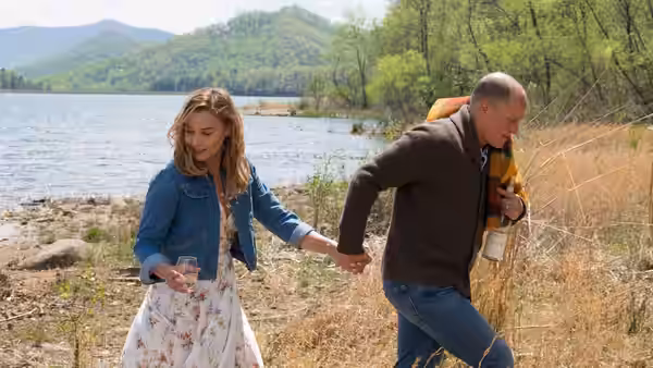 A woman and Dixon (Sam Rockwell) walk by a lake holding hands