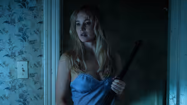 Grace (Jennifer Lawrence) holding a shotgun while standing in a doorway