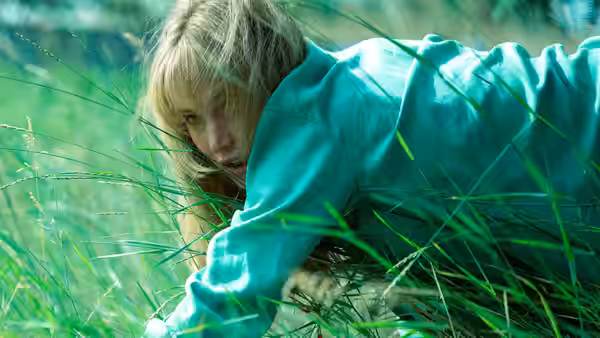 Grace (Jennifer Lawrence) crawling through tall grass in a field