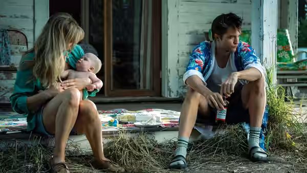 Grace (Jennifer Lawrence) cradling a baby on porch steps beside Jackson (Robert Pattinson)