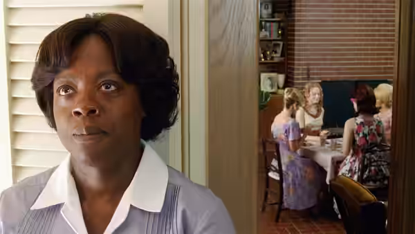 Aibileen Clark (Viola Davis) watches women seated at a dining table