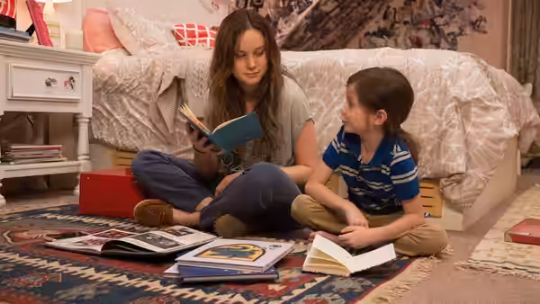 Ma (Brie Larson) reading a book to Jack (Jacob Tremblay) on bedroom floor