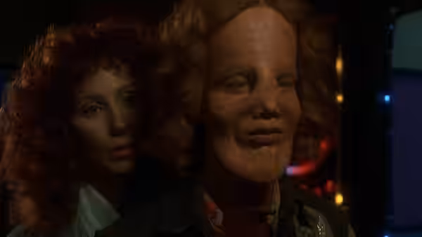 Rusty Dennis (Cher) stands close behind Rocky Dennis (Eric Stoltz) in a dimly lit room