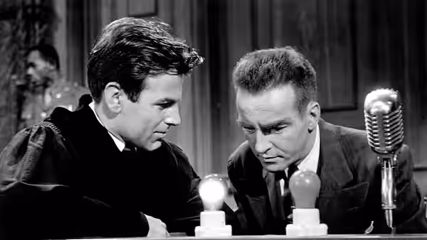 Hans Rolfe (Maximilian Schell) conferring with another man at the table